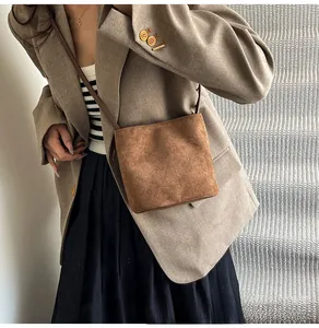 Détail d'un sac bandoulière vintage en daim marron montrant la texture mate et la lanière