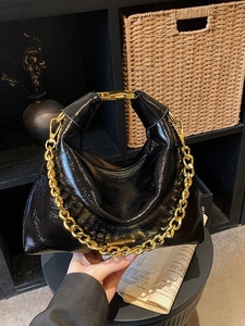 Black patent leather shoulder bag with bold gold chain strap and metallic handle