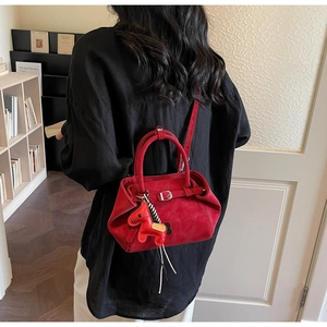 Detail of red matte crossbody bag with buckle decor and small horse charm pendant