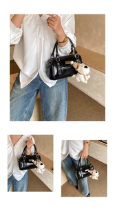 Close-up of black glossy bowling handbag with a cute white plush puppy charm accessory