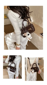 Detail of dark brown glossy bowling bag with a cute white puppy pendant and shoulder strap