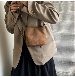 Sac seau en cuir mat marron avec un blazer kaki pour un look élégant et minimaliste