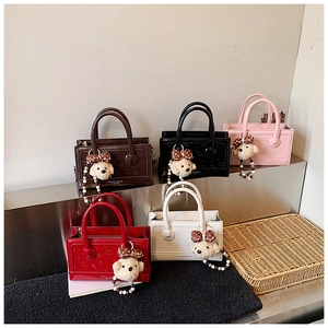 Detailed view of square leather handbags in five colors with teddy bear charms