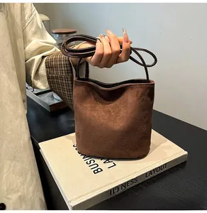 Vue détaillée du sac seau en daim marron givré avec une bandoulière minimaliste