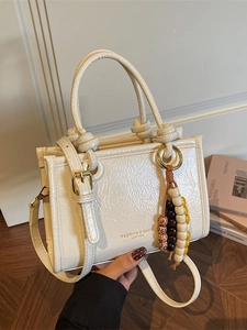 Chic beige ruched leather handbag with knotted handle and colorful bead charm accessory