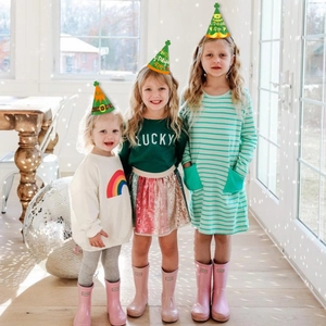 Close-up of children wearing green St. Patrick's Day paper hats with shamrock patterns