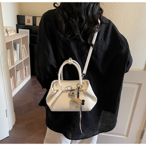 Rear view of a white trapezoid handbag with a leather horse charm in a cozy room