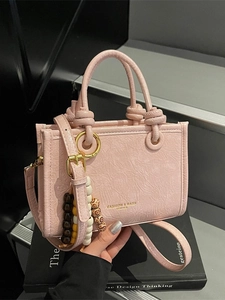 Pink pleated leather bucket bag with top handles and colorful beaded charm
