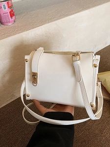 White minimalist leather crossbody bag with gold hardware shown in a lifestyle setting