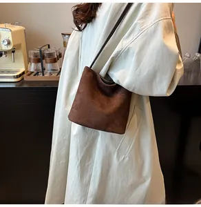 Vue détaillée d'un sac à bandoulière en daim marron foncé mat dans un décor de style de vie