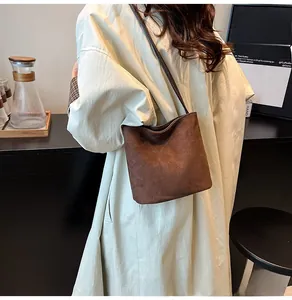 Détail d'un sac bandoulière minimaliste en daim marron givré dans un décor de café