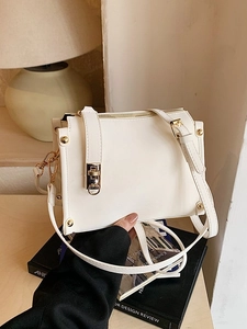 Minimalist white crossbody bag with gold hardware shown in a lifestyle scene
