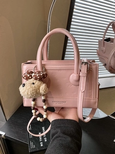 Pink glossy handbag with embossed cartoon puppy and plush pendant accessory