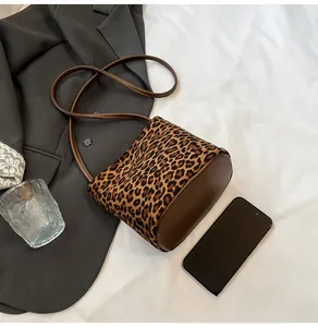 Détail du sac seau à imprimé léopard avec bandoulières en cuir marron et accessoires