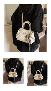 Detailed view of white trapezoid handbag with decorative metal buckle and pony charm accessory