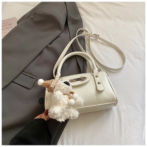 Nahaufnahme der cremeweißen Kissen-Tasche aus Leder mit silbernen Nieten und Anhänger