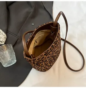 Detail view of leopard print bucket bag interior showing a zippered pocket and brown handle