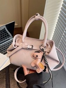 Pink matte leather handbag with horse charm and shoulder strap in an office setting