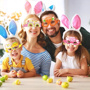 Familie mit Oster-Partybrillen aus Papier und Hasenohr-Stirnbändern in warmer Umgebung
