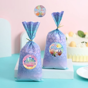 Close-up of mermaid theme party gift bags with scale patterns and round seal stickers