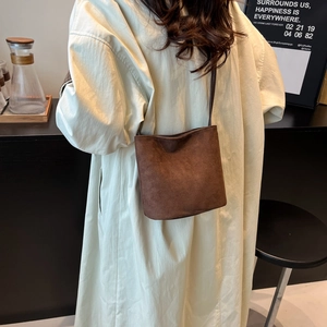 Sac cylindre minimaliste en cuir dépoli marron dans un décor intérieur de style moderne
