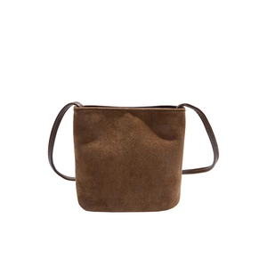 Sac seau minimaliste en daim marron foncé avec bandoulière cuir sur fond blanc