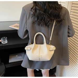 Close-up of cream leather bucket bag with litchi texture and gold buckle details