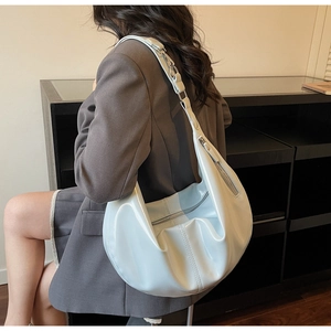 Vue latérale d'un sac hobo bleu clair brillant porté par un mannequin au style moderne