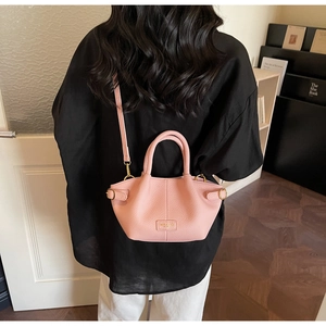 Detailed view of pink lychee textured leather bucket bag with elegant gold hardware