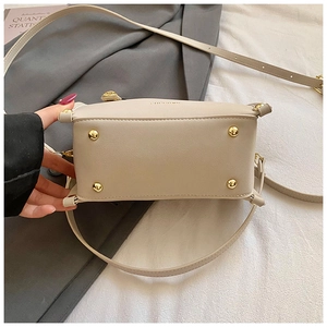 Detail of beige leather handbag bottom with four protective gold metal feet on a neutral fabric