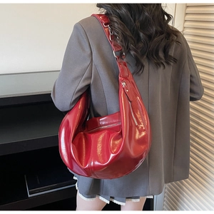 Gros plan sur le sac hobo en cuir verni rouge vif, texture brillante et fermeture éclair