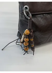 Close-up of dark brown tote bag with leather texture and woven bead charm detail