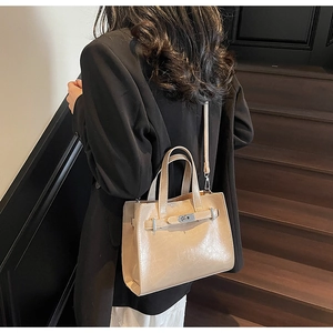 Dettaglio della borsa tote beige con chiusura girevole in argento su modella
