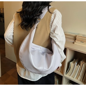 Détail du sac à bandoulière demi-lune lilas porté par un mannequin dans un cadre intérieur chaleureux