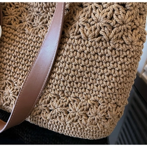 Detail view of coffee straw tote showing floral weave texture and leather strap stitching