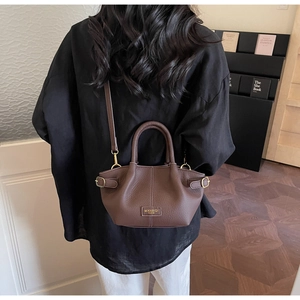 Close-up of brown lychee grain handbag showing adjustable side buckle and leather texture