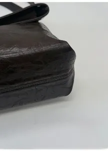 Detail view of the thickened bottom support on a dark brown textured leather tote bag