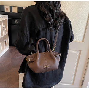 Detailed close-up of dark brown lychee grain leather bucket bag with metal logo