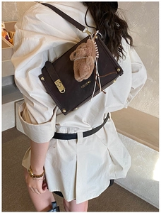 Brown frosted leather crossbody bag detail with metallic lock and plush bear pendant