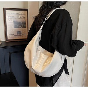Vue détaillée d'un grand sac hobo blanc verni porté à l'épaule pour un style citadin chic