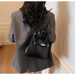 Dettaglio borsa tote in pelle nera lucida con chiusura a rotazione in argento e cinturino
