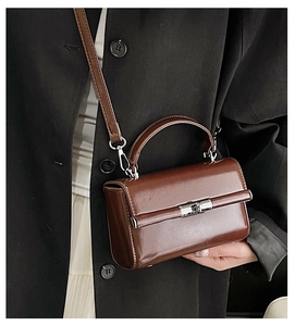 Close-up of a glossy brown small square bag with silver twist-lock and shoulder strap