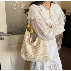 Detail of hollow floral crochet texture and brown leather strap on cream straw shoulder bag