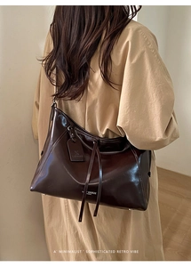 Detail of glossy chocolate leather tote bag with white logo and textured finish