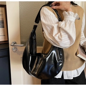 Détail d'un grand sac hobo noir brillant montrant la texture lisse et la fermeture éclair