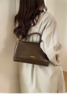 Detail of dark brown tote bag showing leather texture and gold hardware on a model