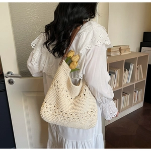 Detail of hollow floral knit tote bag with brown leather strap and decorative tulips