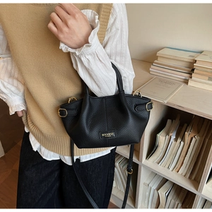 Close-up of black lychee grain leather handbag with vintage buckle and branding