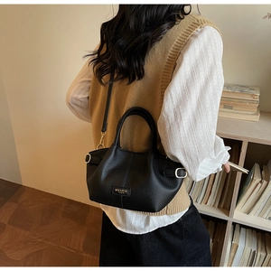 Detailed view of black lychee grain leather handbag styled on a shoulder strap
