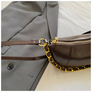 Detail of vintage oil wax leather bag with golden chain and smooth metallic zipper